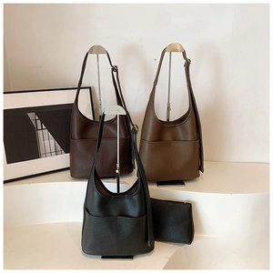Three minimalist leather tote bags in black, dark brown, and tan displayed on metal racks