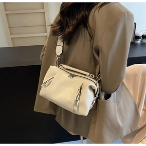 Close-up of beige lychee leather bag with pleated detail and adjustable wide shoulder strap