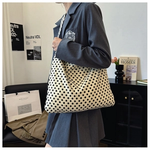 Stylishly oversized canvas tote bag with polka dots shown worn by model in grey blazer