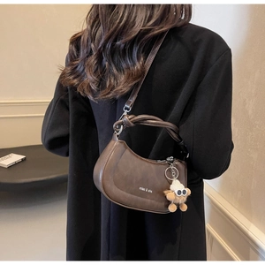 Detailansicht der braunen Hobo-Satteltasche mit Knotengriff und Plüschbär-Anhänger-Zubehör