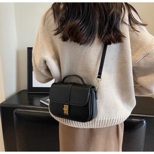 Rear view of model wearing black lychee texture crossbody bag with gold hardware