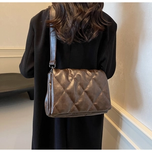 Detailed back view of brown quilted crossbody bag with glossy faux leather finish