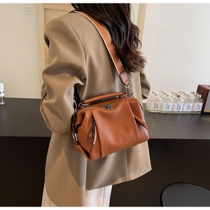 Detail of caramel brown textured leather pillow bag with wide woven shoulder strap