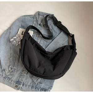 Detail of minimalist black crescent bag with adjustable strap on denim background