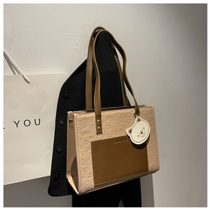 Detailansicht der beigen Tragetasche mit Reliefmuster und brauner Kontrasttasche