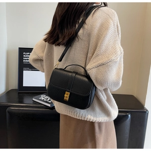 Detail of black lychee grain leather crossbody bag with golden square metal buckle