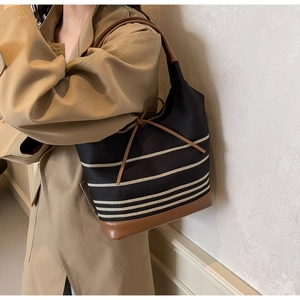 Detail of striped canvas tote bag with brown faux leather trim and ribbon drawstring closure