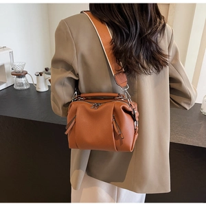 Detail of caramel pleated boston bag with textured leather and wide woven shoulder strap