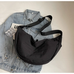 Close-up of black nylon crescent crossbody bag with adjustable wide strap on jacket