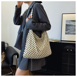 Detailed close-up of large canvas tote bag with black polka dots and side woven label