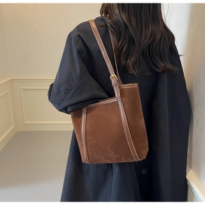 Detailed back view of vintage brown suede tote bag worn over shoulder on creamy background