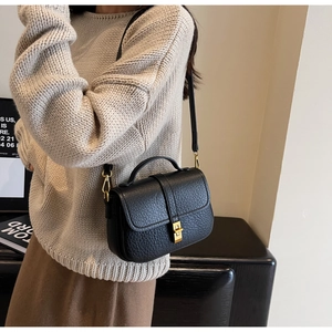 Close-up of black litchi pattern leather bag with elegant golden twist lock detail