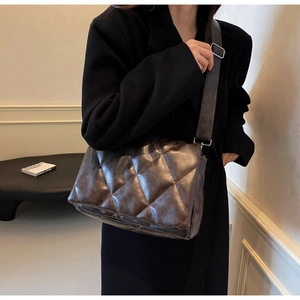 Detail of adjustable wide strap and silver buckle on quilted brown faux leather tote bag