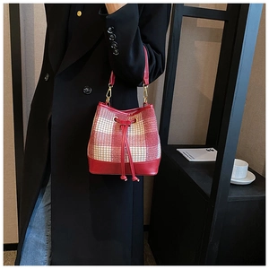 Détail du sac seau en tweed à carreaux rouges avec cordon et lanière en cuir
