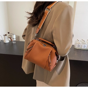 Brown lychee texture crossbody bag with wide shoulder strap shown on a model