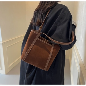 Detail view of the deep brown suede tote bag texture and adjustable leather strap
