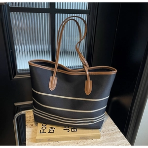 Detailed close-up of a striped canvas tote bag with brown leather handles and base details
