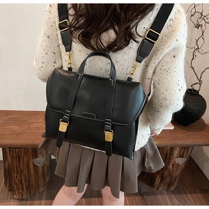 Detail eines schwarzen Retro-Rucksacks mit goldenen Schnallen und matter Lederoptik