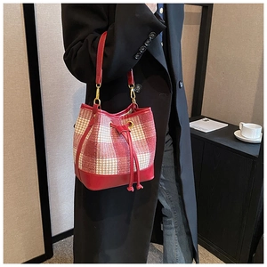 Détail du sac seau à carreaux rouge et blanc avec sangle en cuir et cordon de serrage