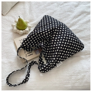 Detail of black canvas tote with white polka dots and EMIS woven label on side