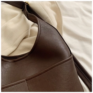 Detailed view of dark brown semi-moon shoulder bag with fine texture and gold buckle