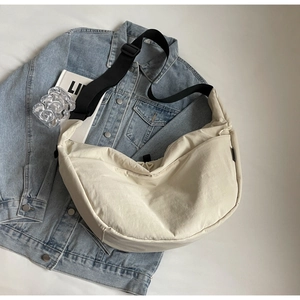 Detail view of cream crescent crossbody bag with adjustable wide black strap