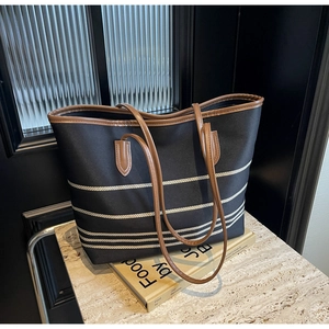 Classic black and white striped canvas tote bag with brown leather handles on art books