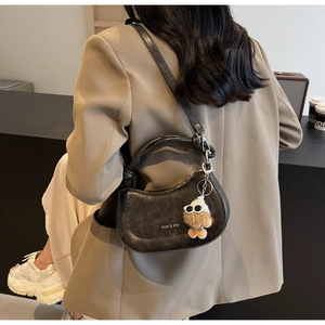 Modell trägt eine schwarze Satteltasche mit Plüschanhänger und schlichtem Logo
