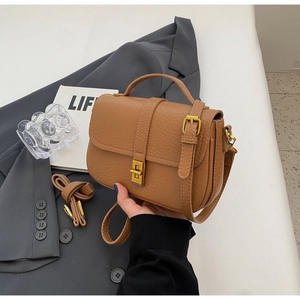Detail of vintage brown textured leather handbag with gold clasp on grey blazer suit