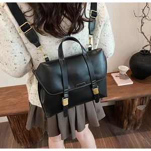 Detail view of retro black leather backpack with gold buckles in a warm home setting