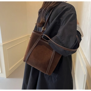 Dark brown suede tote bag shown on a model with premium shoulder strap details