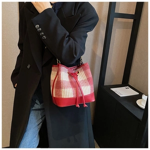 Détail du sac seau pied-de-poule rouge et blanc avec cordon et bandoulière chaîne