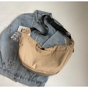 Detailed close-up of khaki crescent messenger bag with adjustable strap on denim