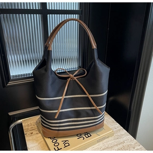 Detailed close-up of a large canvas tote bag with brown leather handles and bow decoration