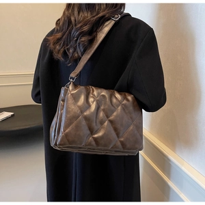 Detail of dark brown quilted crossbody bag shown on model for size and drape reference