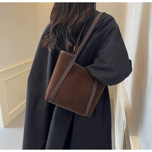 Rear view of a model wearing a brown suede tote bag over a stylish black jacket