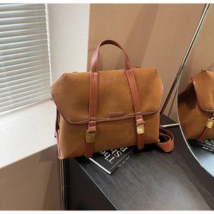 Detailaufnahme der braunen Wildledertasche mit dunklen Lederriemen und Bronzeschnallen