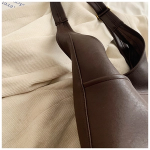 Detail of chocolate leather hobo bag showing fine stitching and metal strap buckle