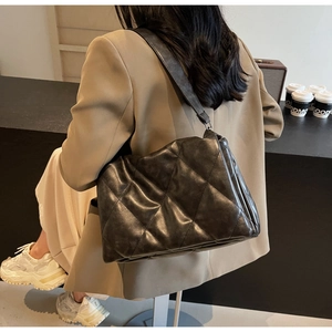 Close-up of quilted black leather shoulder bag showing rhombus pattern and soft texture