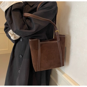 Detail of retro dark brown suede tote bag with leather trim and gold adjustable strap