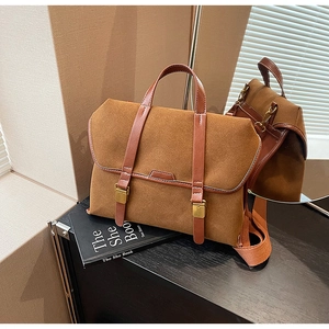 Detailansicht der karamellfarbenen Wildleder-Handtasche mit Metallschnallen und Lederriemen
