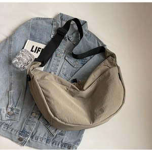 Detail of khaki crescent crossbody bag on denim jacket with life magazine and minimal decor