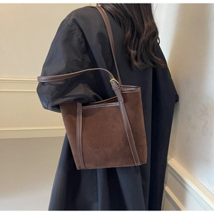 Close-up of brown matte suede tote bag with leather trim and adjustable buckle details