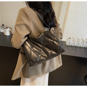 Chic black quilted crossbody bag with diamond patterns worn by a model in a cafe setting