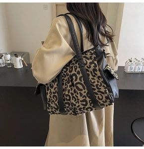 Detailed side view of large leopard print tote bag with black leather trim and straps