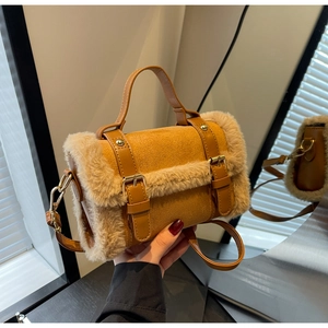 Dettaglio di ecopelliccia e fibbia dorata su borsa in pelle scamosciata marrone