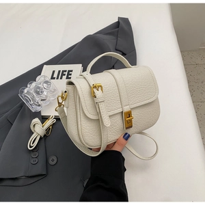 Detailed macro view of beige lychee grain leather handbag with gold metal twist lock