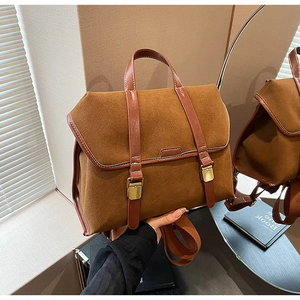 Detail eines braunen Rucksacks aus mattem Wildleder und Leder mit Goldmetallschnallen
