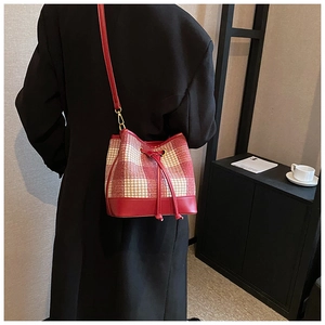 Détail du sac seau à carreaux rouges avec base en cuir et cordon de serrage doré