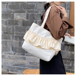 Detail of white canvas tote bag with yellow ruffled pleats and comfortable shoulder strap